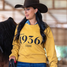 Load image into Gallery viewer, Woman wearing a yellow sweatshirt with 'Since 1936' text, standing next to a horse in a barn.
